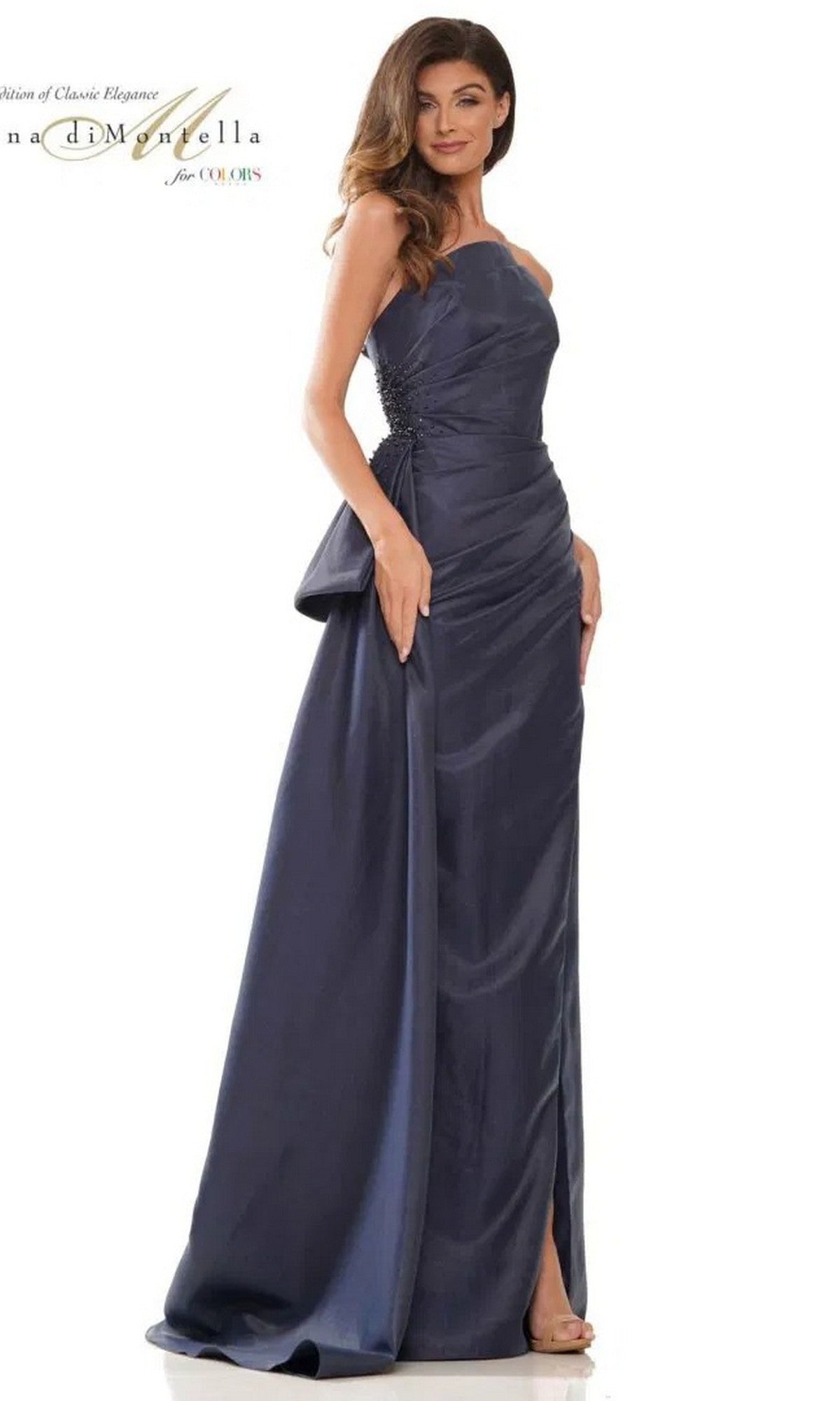 A woman poses against a white background wearing the Rina Di Montella RD2750 long formal dress in navy, featuring a strapless sheath silhouette with a side slit and gathered ruching.